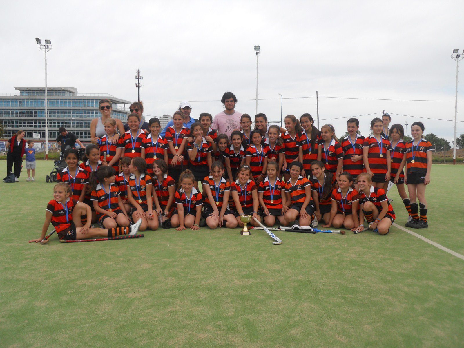 Equipo de hockey infantil de Olivos con una copa en la cancha