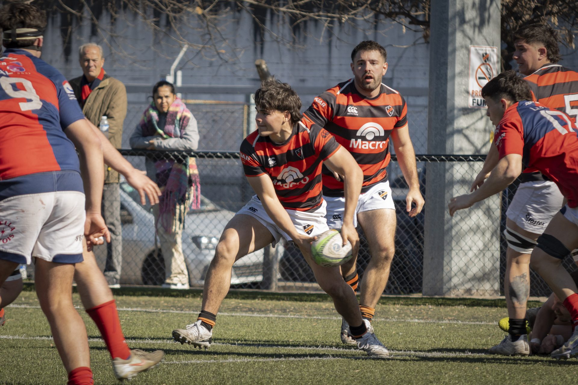 Jugador de Olivos a punto de pasar la pelota, con un compañero en apoyo